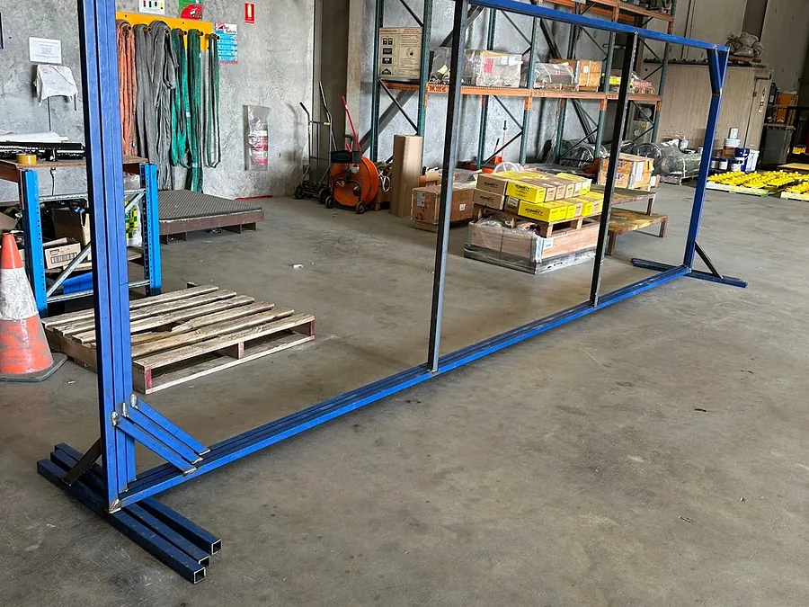 A large fabricated steel welding screen frame standing on its feet on the workshop floor