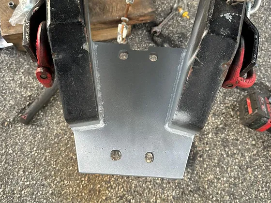 A welded and drilled steel plate fitted between the drawbar members of a custom trailer hitch